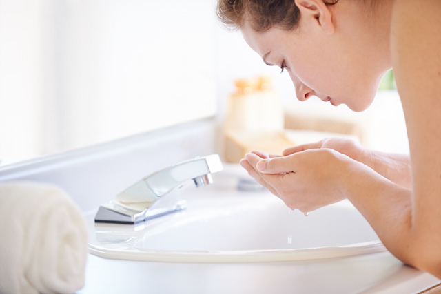 Woman washing her face with NEUTROGENA® to help keep skin clear