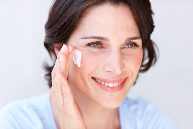 Woman applying NEUTROGENA® moisturizer to face with a cotton pad