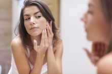 Femme examinant sa peau dans le miroir