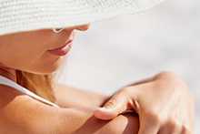 Woman applying NEUTROGENA® sunscreen to back